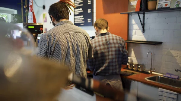 Kahve dükkanının iki çalışanı kahve hazırlıyor. Madde. İki genç barista küçük kahve dükkanında çalışmak ve profesyonel kahve hazırlamak — Stok fotoğraf