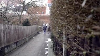 İnsanlar bulutlu sonbahar gününde şehir yolunda yürürler. Madde. İnsanlar bulutlu havalarda şehir şeridinde çit ve zanaat duvar arasındaki yol boyunca yürümek