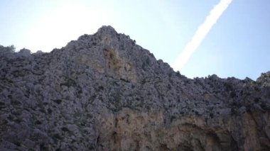 Mavi gökyüzünün arka planında dağ tepe kayalar üzerinde alt görünümü. Madde. Mavi gökyüzünün arka planında seyrek bitki örtüsü ile aşağıdaki kayaların zirvelerinin dağ panoraması