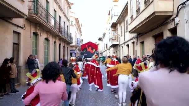 西班牙，巴塞罗那-13四月2019：服装游行通过节日的街道的城市。艺术。身着不同服装的年轻人在狭窄的街道上庆祝节日 — 图库视频影像