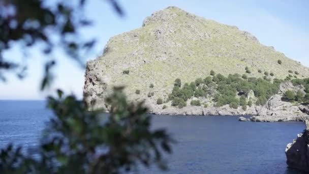 Pintoresca vista del mar azul y la costa rocosa de la montaña verde. Art. Hermoso paisaje marino con acantilados rocosos cubiertos de vegetación verde y con azul marino contra el cielo azul claro — Vídeo de stock