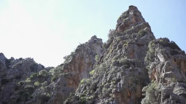 Vista dal basso su cima di montagna rocciosa su sfondo di cielo. Art. Montagne rocciose naturali panoramiche con dossi e sporgenze nelle limpide giornate estive — Video Stock