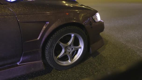 Close-up de roda e corpo de carro brilhante. Acção. Revestimento de design de carro com lantejoulas douradas cintilantes à luz das luzes noturnas da estrada da cidade — Vídeo de Stock