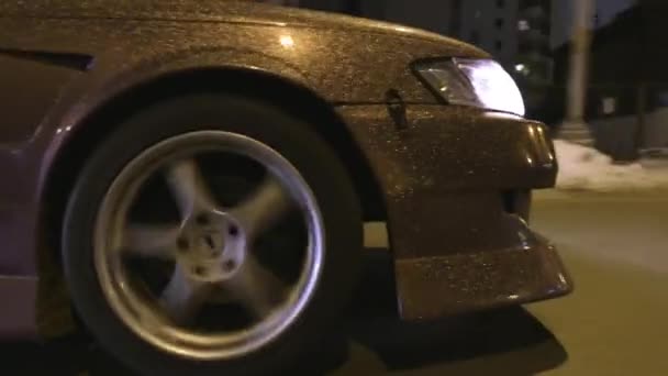 Close-up of glitter on car. Action. Modern design of car coating with gold sequins glittering from light of lanterns on night urban track — Stock Video