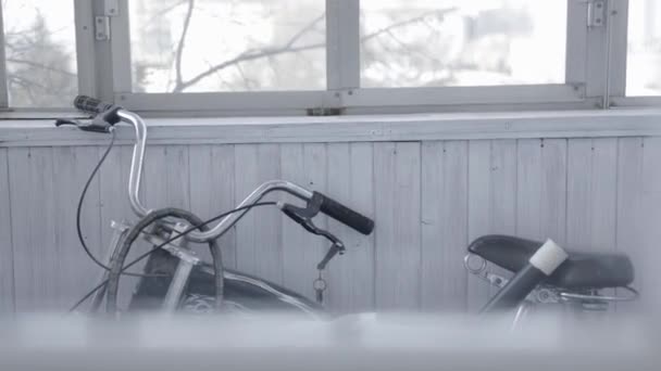 Schwarzes Fahrrad steht auf grauem Holzbalkon. Aktion. Hochgeschwindigkeits-altes Fahrrad steht auf geschlossenem, klaren Balkon mit Fenstern und wartet auf den Sommer — Stockvideo