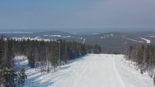 Pintoresca vista del complejo deportivo y recreativo para vacaciones de invierno, concepto de estilo de vida saludable. Filmación. Aérea para jóvenes adolescentes snowboard y esquí en la colina sobre el fondo del bosque de invierno . — Vídeos de Stock