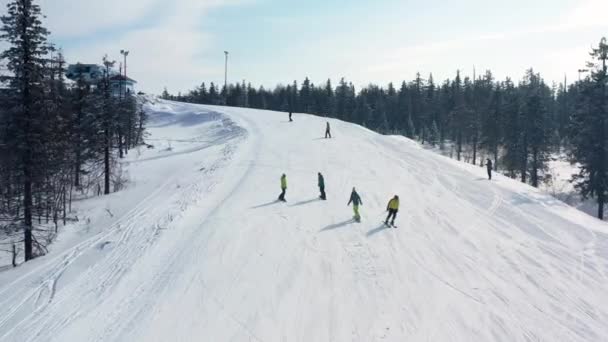 Aérea para pistas nevadas con un grupo de personas esquiando y haciendo snowboard en un día soleado, concepto deportivo peligroso. Filmación. Hombres y mujeres haciendo deportes de invierno . — Vídeos de Stock