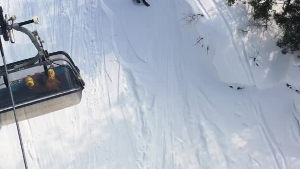 Vista aérea superior de um funicular em movimento com pessoas sentadas nele no fundo da encosta nevada. Filmagem. Teleférico na floresta nevada, esporte e conceito de férias . — Vídeo de Stock