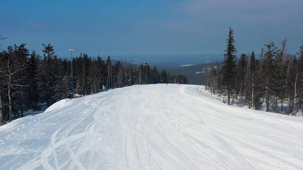 Vista pitoresca do esporte e recreação resort para férias de inverno, conceito de estilo de vida saudável. Filmagem. Aéreo para jovens adolescentes snowboard e esqui descendo a colina no fundo da floresta de inverno . — Fotografia de Stock