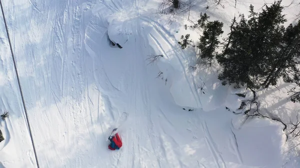 Vista superior aérea de um snowboarder que monta da colina de neve de pó muito rápido e que cai. Filmagem. Homem boarder pulando de uma colina e caindo, conceito de esporte . — Fotografia de Stock