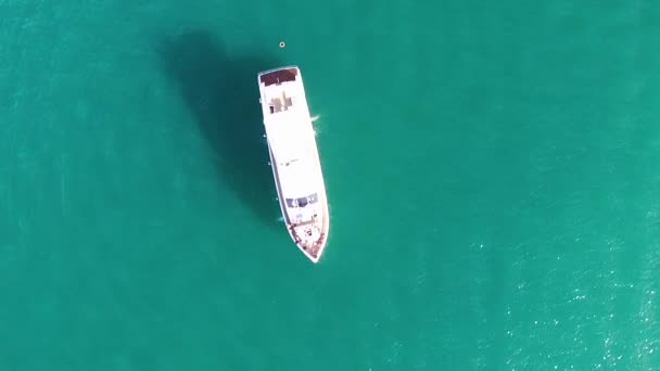 Aerial drone pássaro olho vista superior do iate bonito branco em águas cristalinas turquesa da Grécia. Estoque. Fundo de água azul-turquesa com navio branco, paisagem marinha de verão . — Vídeo de Stock