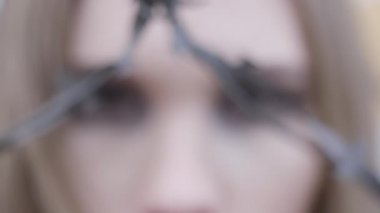 Dikenli tellerle genç bir kadının gözlerinin yakın çekimi. Eylem. Güzellik moda konsepti