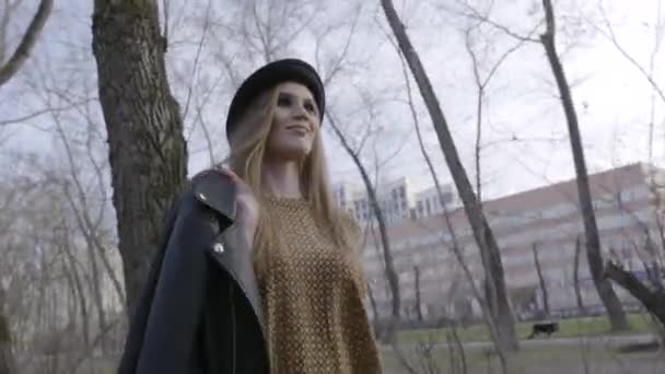 Aantrekkelijke jonge vrouw genieten van haar tijd buiten in Park met zonsondergang. Actie. Mooie jonge vrouw in hoed wandelen in het Park — Stockvideo