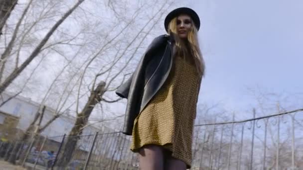 Atractiva joven mujer disfrutando de su tiempo al aire libre en el parque con puesta de sol. Acción. Hermosa joven con sombrero caminando en Park — Vídeos de Stock