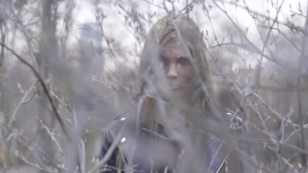 Beautiful young woman behind the bushes in autumn. Action. A woman from behind the bushes looking at the camera — Stock Video