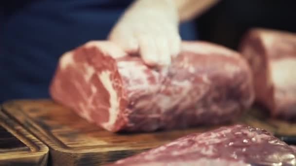 Primer plano de las manos del carnicero con guantes protectores blancos que preparan un gran corte de carne para cocinar o vender. Acción. Trabajo de carnicero — Vídeo de stock