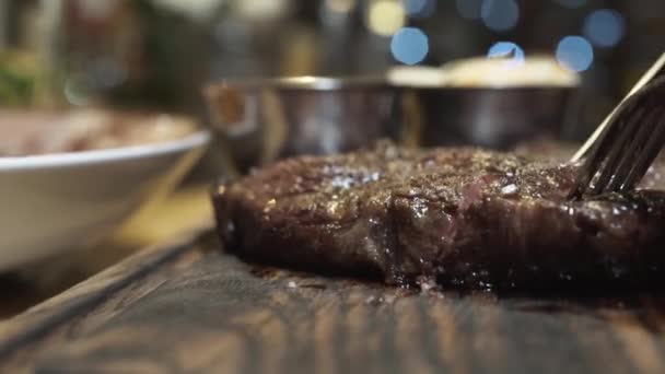 Hot juicy steak cut with knife on a wooden board in close-up view. Medium Rare degree of steak doneness — Stock Video