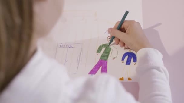 Kisgyermek húz egy ceruzát egy papírlapra. Akció. Egy fiatal lány felhívja a papírlapra. Egy ajándék az anyának — Stock videók