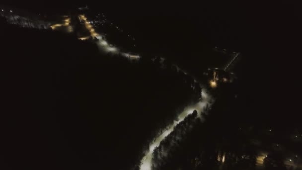 Top uitzicht op de Winterweg in het bosgebied 's nachts. Clip. Besneeuwde weg verlicht door lantaarns 's nachts — Stockvideo