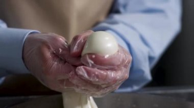Elleriyle mozzarella kesen bir peynircinin elleri için kapatın, geleneksel gıda konsepti. Çerçeve. Lezzetli İtalyan peyniri yapma süreci.