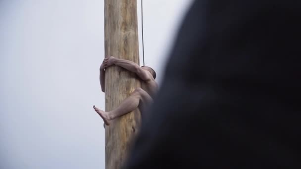 O homem sobe o poste no carnaval. Clipe. Pessoa sobe no pólo atrás de presentes enquanto Shrovetide festividades — Vídeo de Stock