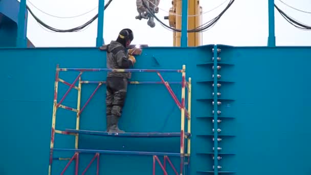 Werkende man lassen stalen frame site bouw. Clip. Man in het masker maakt Lasconstructies op de bouwplaats — Stockvideo