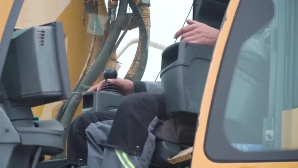 Grúa de operador de ingeniería en acción. Clip. El hombre en cabina controla la grúa. Se sienta en una cabina de grúa y trabaja — Vídeo de stock