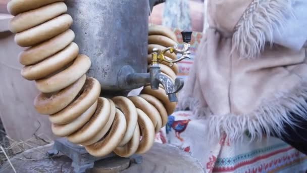 Samovar tradicional com bagels. Clipe. Samovar de bronze russo tradicional, um símbolo de hospitalidade. Bagels crocantes, secagem ou bagels pendurados no samovar — Vídeo de Stock