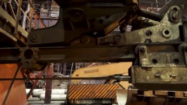 Arka planda koruyucu üniformalı işçilerle fabrikada bir hareketli mekanizmanın detayı için yakın. Stok görüntüleri. Metalurji tesisinde iş makinesi.