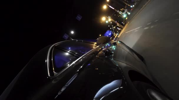 O carro da noite dirigindo no final da noite, vista da roda, conceito de vida noturna. Filmagem. Fechar para mover carro preto através da rua da cidade noite . — Vídeo de Stock