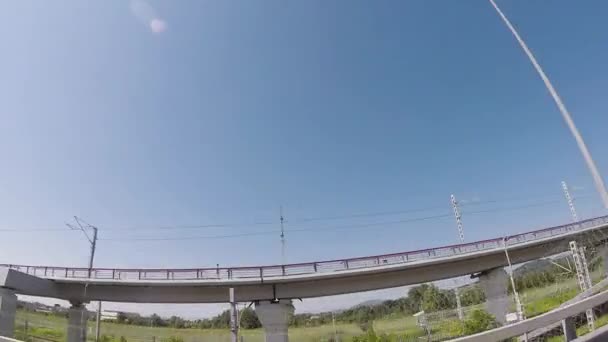 Вид з вікна автомобіля на сучасному мосту в сонячний день з красивим блакитним небом на фоні, ефект Фішея. Сцена. Вид знизу від автомобіля на пішохідний міст . — стокове відео