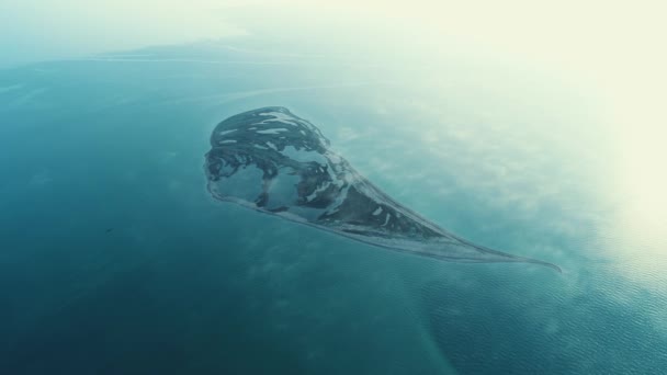 Niesamowity widok z lotu ptaka w kształcie twarzy z dużymi jeziorami i ciemnobrązowej ziemi w środku morza w słoneczny dzień. Strzał. Samotna wyspa w morzu — Wideo stockowe