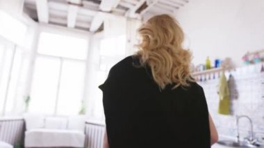 Beyaz tişörtlü, kot pantolonlu ve siyah kazaklı güzel sarışın kadının yakın çekim ilerki. Eylem. Evde rahatlatıcı