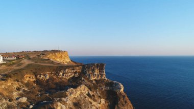 Mavi berrak gökyüzü ve mavi deniz suyuna karşı büyük bir uçurumun üzerinde duran insanların havadan görünümü. Atış. Yukarıdan güzel manzara
