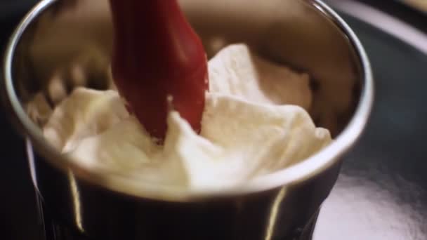 Primer plano de crema dulce blanca exprimida en una pequeña taza de acero en una cocina. Una trampa. Preparación de postres — Vídeo de stock