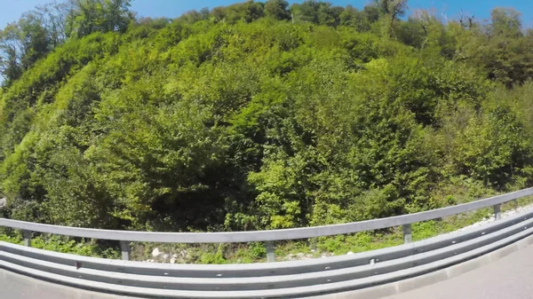 Skalisty krajobraz wzdłuż drogi, widok z okna poruszający się samochód na drogach Krymu, efekt rybie oko. Sceny. Zielona roślinność w górach na tle błękitnego nieba. — Zdjęcie stockowe