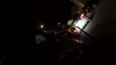Gece şehir caddesinde park etmiş siyah bir arabanın arka görünümü, gece trafik konsepti. Görüntü. Neon parıldayan ışıkları ile binek araç sokakta park.