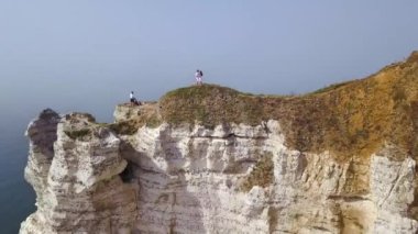 Denizde beyaz uçurumun zirvesinde duran turistlerin en iyi görünümü. Eylem. Büyük beyaz uçurum, mavi deniz ve turistlerin kenarında yürüyüş muhteşem manzarası