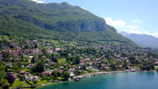 Cottage town on background of mountain and blue lake. Action. Top view of paradise vacation spot in country town in wooded area with coastal mountains by turquoise lake in summer — Stock Video