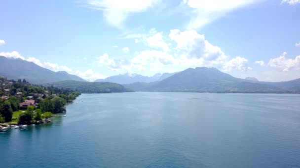 Panorama de lago, montanhas e casas perto da costa. Acção. Vista superior do pitoresco lago azul, costa com chalés para férias de campo no verão e montanhas no horizonte — Vídeo de Stock