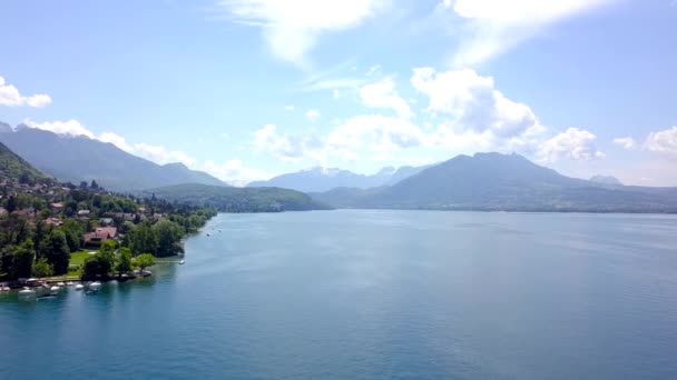 Panorama du lac, des montagnes et des chalets près du rivage. L'action. Vue de dessus du lac bleu pittoresque, rivage avec chalets pour des vacances à la campagne en été et montagnes à l'horizon — Video