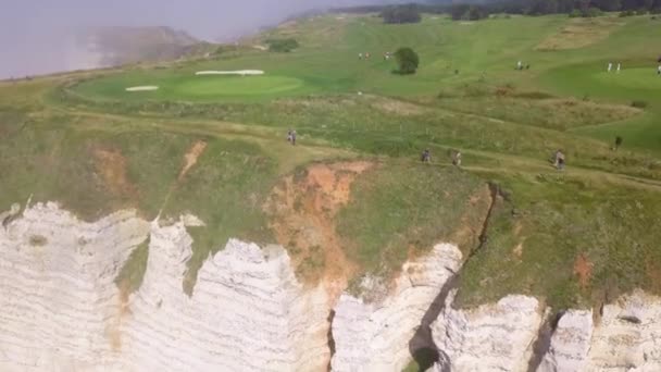 Vue de dessus des touristes marchant sur le pic vert à la falaise de la falaise blanche. L'action. Vue panoramique sur la falaise côtière avec des lignes laissées par l'érosion du vent de la mer. Beauté naturelle et touristes voyageurs 