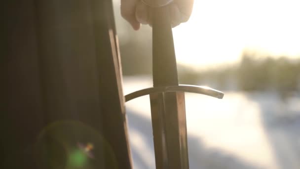 Homem de fato medieval a segurar espada. Acção. Close-up de homens mão em terno medieval segurando punho espada no fundo da luz solar. Vista épica do herói medieval — Vídeo de Stock