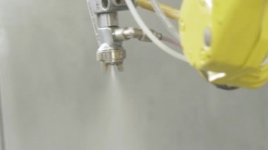 Otomatik üretimde boya ile sprey tabancası. Eylem. Fabrika üretiminde boyama parçaları ile çalışan robot el spreyi ile yakın çekim otomatik. Üretimde otomatik yüksek teknolojiler