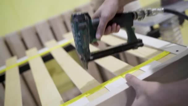 Closeup of worker holds board with stapler. Action. Worker uses stapler to bond tape with wood boards in furniture factory — Stock Video