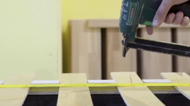 Closeup of worker holds board with stapler. Action. Worker uses stapler to bond tape with wood boards in furniture factory — Stock Video