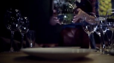 Kadın masaya çiçek vazosu koyar. Eylem. Kadının yakın çekim karanlık arka plan üzerinde gizemli ışıklar ile hizmet masaya beyaz çiçek vazo koyar