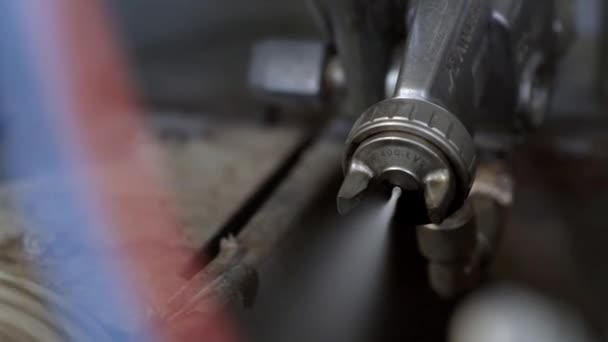 Pistola de pulverização para pintura na produção industrial. Acção. Close-up de pistola de pulverização moderna mecanizada com tinta branca na fabricação — Vídeo de Stock