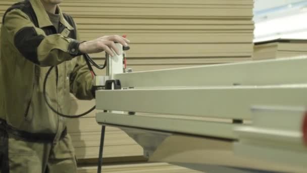 Člověk v přesekech ovládá stroj na dřevo. Akce. Uzavření zaměstnance pracující s moderním průmyslovým strojem na zpracování dřeva v nábytkářském podniku — Stock video
