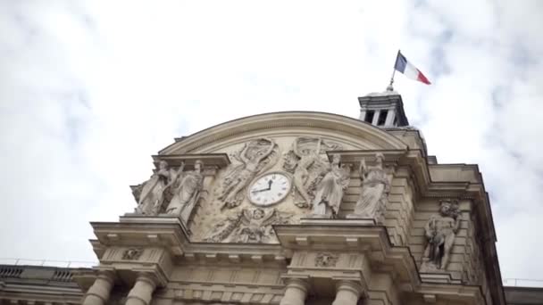 Prachtige oude kapel met reliëf standbeelden. Actie. Verbazingwekkende klok van Luxemburg paleis met zwaaiende vlag van Frankrijk. Klok is versierd met sculpturen en reliëfs van godinnen. Kunstwerk — Stockvideo